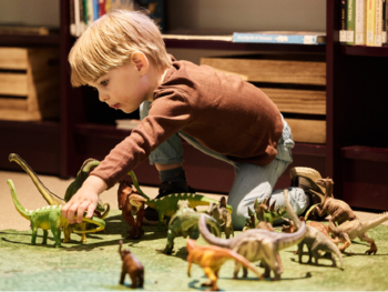 En liten gutt leker med dinosaurus-figurer