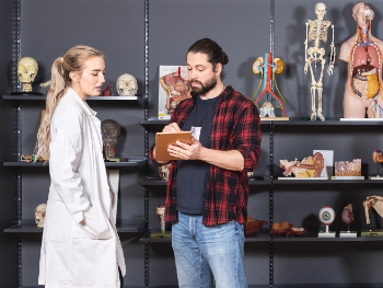 Mann og kvinne snakker sammen med medisinske modeller i bakgrunnen