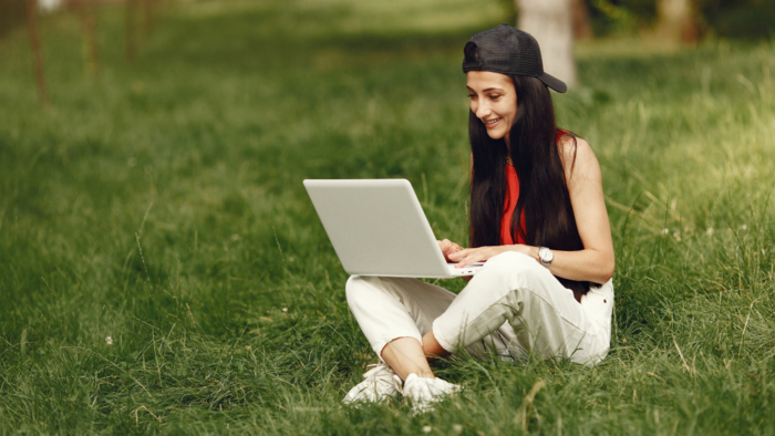 Photo of a student sitting on the grass with a laptop 